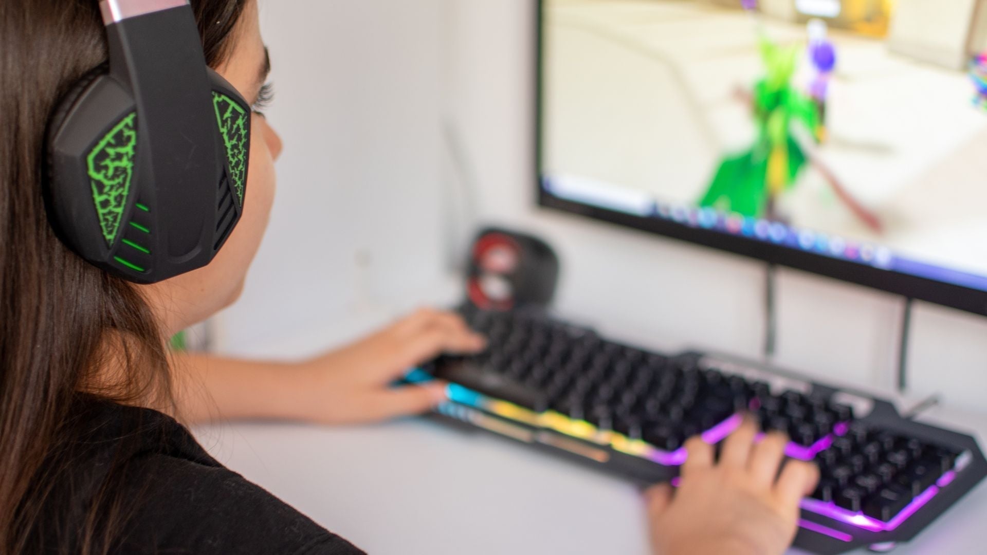 Young girl concentrated, playing video games on her computer with a headset